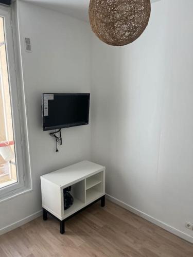 un salon avec une télévision et un meuble blanc dans l'établissement Studio refait à neuf Clichy centre, à Clichy