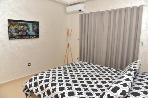 a bedroom with a black and white comforter on a bed at Golf Royal appartement in Fès