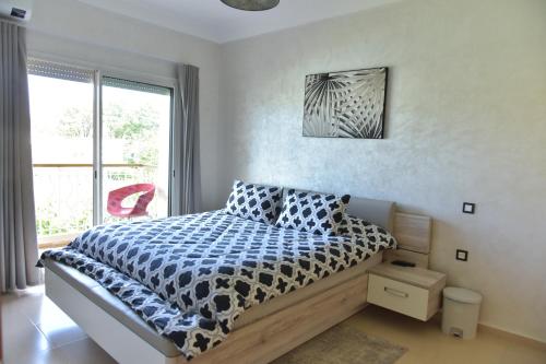 a bedroom with a bed with a blue and white comforter at Golf Royal appartement in Fès