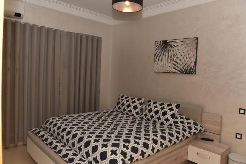 a bedroom with a bed with a black and white comforter at Golf Royal appartement in Fès