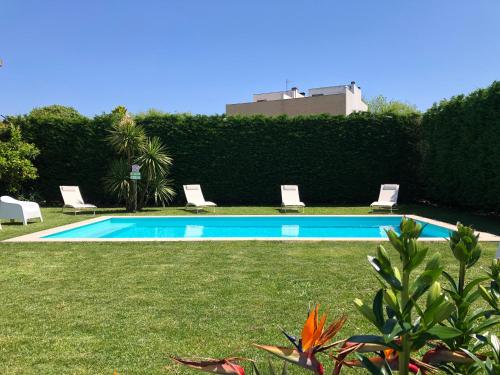 a swimming pool with two lawn chairs and a hedge at Casa Pedro e Inês in Viana do Castelo
