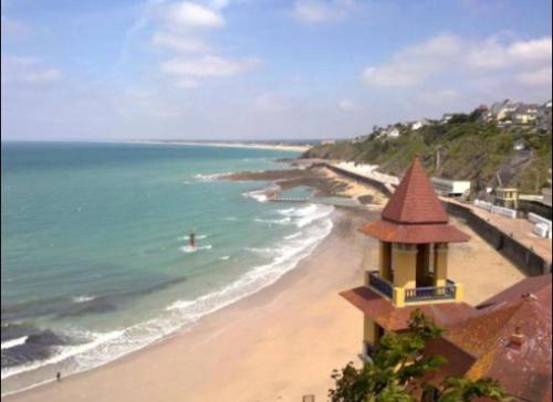 a view of a beach with a building and the ocean at Gîte à la campagne in Le Mesnil-Villeman