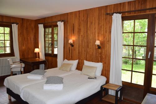 - une chambre avec un lit doté de draps blancs et de fenêtres dans l'établissement Chalet L Olan 15p Emplacement exceptionnel grand terrain, à Les Deux Alpes