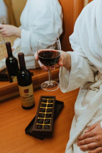 a person holding a glass of wine on a table at Hotel Korona Wellness, Rendezvény és Borszálloda in Eger