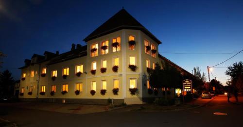 ein großes weißes Gebäude mit beleuchteten Fenstern in der Nacht in der Unterkunft Hotel Korona Wellness, Rendezvény és Borszálloda in Eger