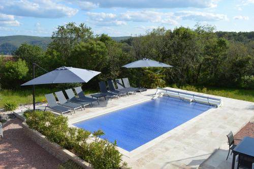 a swimming pool with chairs and umbrellas at La Tourelle du Lot in Cajarc