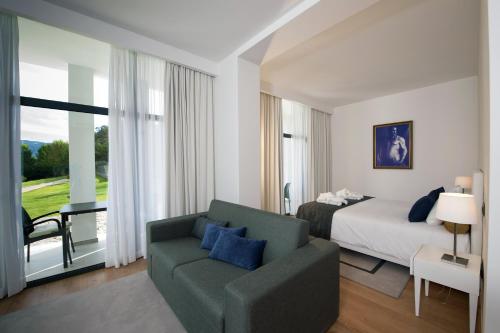 a hotel room with a bed and a couch at Hotel Parque Serra da Lousã in Miranda do Corvo
