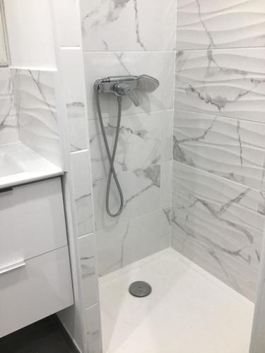 La salle de bains est pourvue d'une douche et de murs en marbre blanc. dans l'établissement Charmant Appartement, à Fréjus