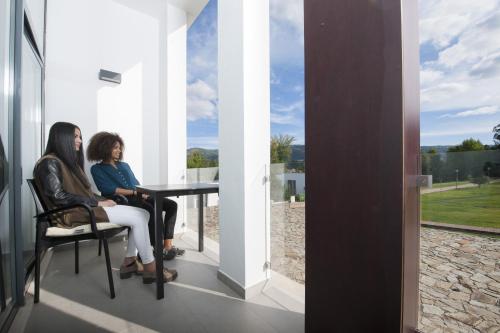 two women sitting at a table on the balcony of a house at Hotel Parque Serra da Lousã in Miranda do Corvo