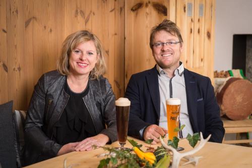 a man and a woman sitting at a table withbeer at Gasthof Hubertus in Saalfelden am Steinernen Meer