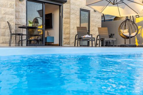 a swimming pool with chairs and an umbrella at אחוזת רוטצ'י - יוקרה בגליל in Safed