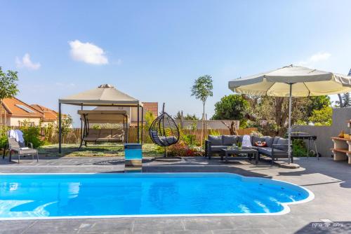 a swimming pool with a swing and an umbrella at אחוזת רוטצ'י - יוקרה בגליל in Safed