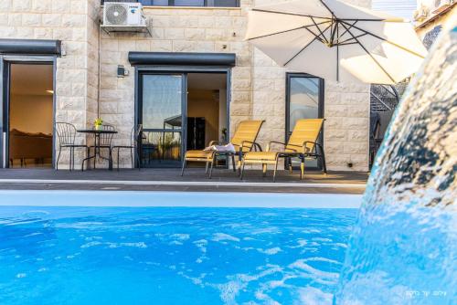 a pool with a table and chairs and an umbrella at אחוזת רוטצ'י - יוקרה בגליל in Safed