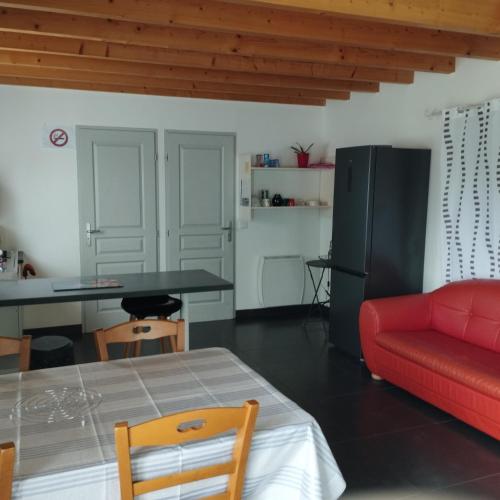 a living room with a red couch and a table at Studio entre terre et mer in Saint-Romain-de-Benet