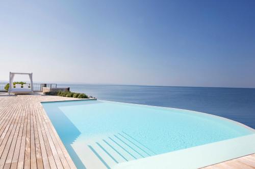 a swimming pool with the ocean in the background at Portopiccolo Apartments in Sistiana