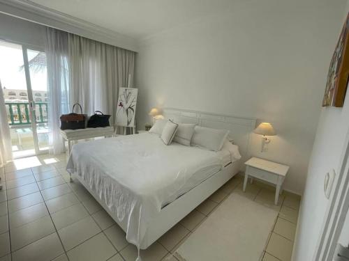 a white bedroom with a large bed and a window at Appartement Sur La Plage in Hammamet