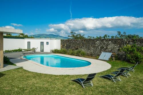 a swimming pool with two chairs and a table at TableTop by Azorean Living in São Roque