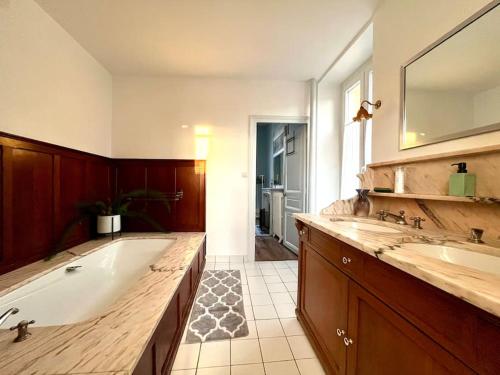 Un baño grande con bañera y dos lavabos. en La Demeure de Margot - 24 couchages, en Villeneuve-sur-Yonne
