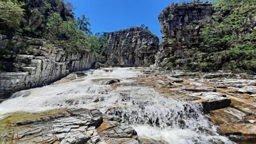 a waterfall in a rocky canyon with trees at Cachoeiras Pé da Serra in São João Batista do Glória