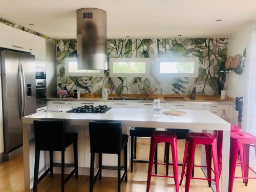 een keuken met een groot wit eiland met roze krukken bij Pop Bohèm en Camargue maison atypique 135m2 in Arles