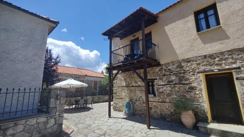 a stone building with a balcony and an umbrella at The Stone House in Halkidiki in Vávdhos