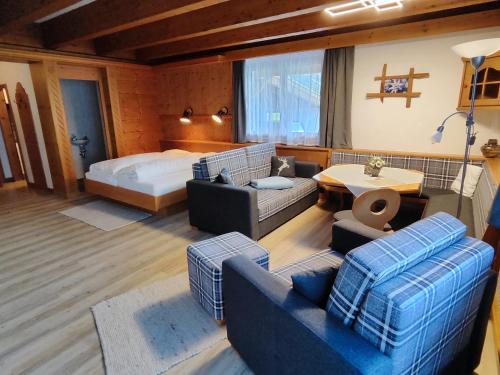 ein Wohnzimmer mit einem Bett, einem Sofa und Stühlen in der Unterkunft Apartmenthaus Bader in Leutasch