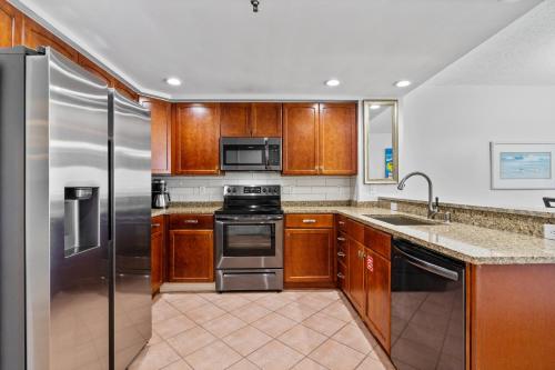 una cocina con armarios de madera y electrodomésticos de acero inoxidable en Emerald Isle Unit 607, en Pensacola Beach