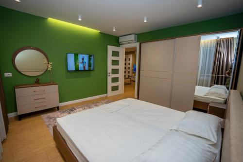 1 dormitorio con paredes verdes, 1 cama y espejo en Vila Klaro, en Shkodër