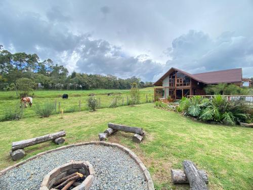 a house with a yard with logs in front of it at Chalet del lago Santa Elena in Santa Elena