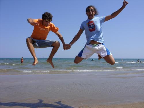 two men jumping in the air on the beach at Villaggio Camping Oasi in Vieste