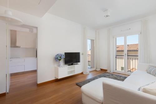a white living room with a white couch and a tv at Portopiccolo Apartments in Sistiana