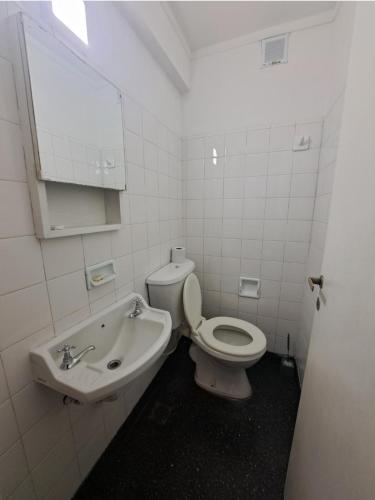 a white bathroom with a toilet and a sink at Plaza 23 in Bahía Blanca