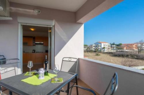 a table with wine glasses on a balcony at Apartmani Maja Vrsi in Vrsi