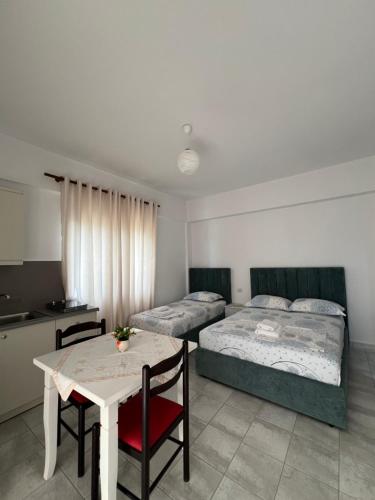 a bedroom with two beds and a table and a kitchen at Dea Apartament in Ksamil