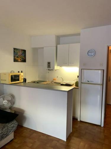 une cuisine blanche avec un réfrigérateur et un micro-ondes dans l'établissement Studio centre port, Cap d'Agde, au Cap d'Agde