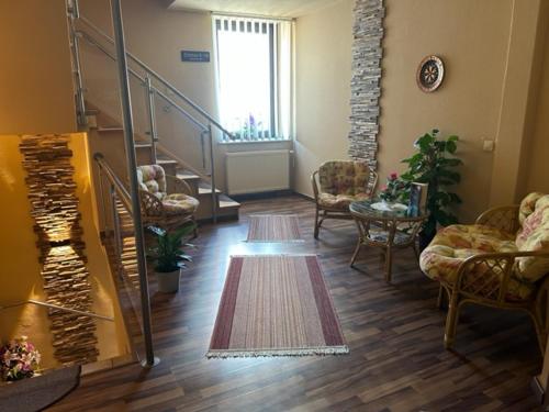 a living room with a staircase and chairs and a rug at Pension Krahmer in Chemnitz
