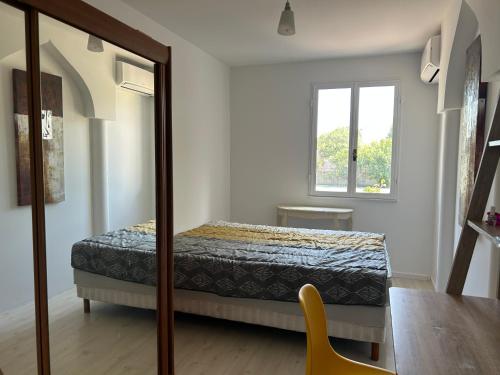 Schlafzimmer mit einem Bett, einem Tisch und einem Fenster in der Unterkunft Maison de charme en bord de mer in Lucciana