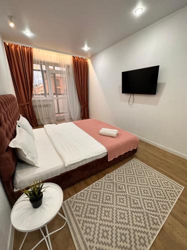 a bedroom with a bed and a flat screen tv at ЖК МАДИНА ЕВРА ДВУШКА in Kokshetau
