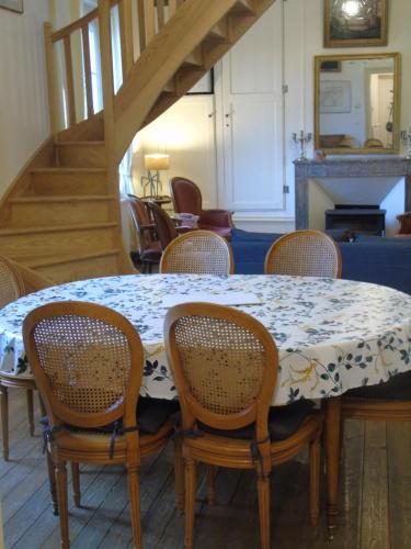 une salle à manger avec une table, des chaises et un escalier dans l'établissement Petit Argousier, à Cambron