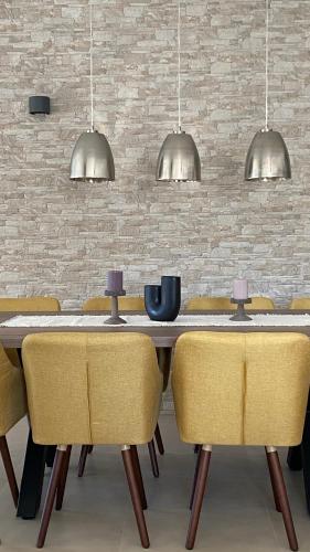 a dining room with a table and yellow chairs at Villa Milandro - Luxus & Ruheoase in Lašći