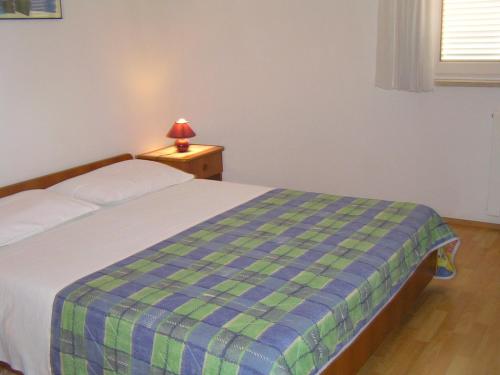 a bedroom with a bed with a blue and green plaid blanket at Apartments Paloma blanca 1 in Medulin