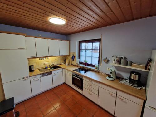 a kitchen with white cabinets and a wooden ceiling at Eifel Ferienhaus Luna in Ohlenhard