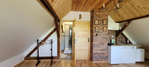 a kitchen with wooden ceilings and a brick wall at Gryglówka Noclegi in Zembrzyce
