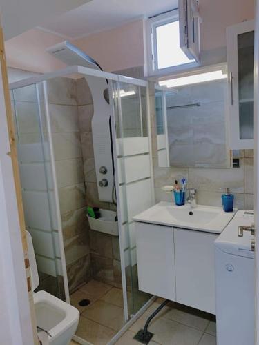 a white bathroom with a toilet and a sink at Panoramic Sea View in Porto Rafti