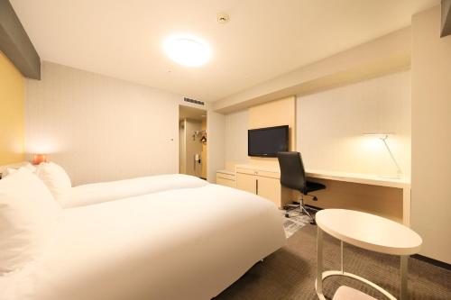 Habitación de hotel con cama blanca y escritorio en Richmond Hotel Narita en Narita
