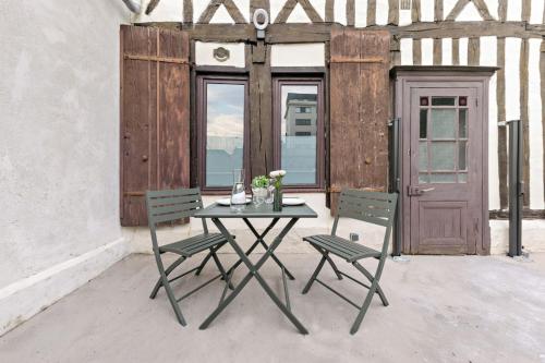 - une table et deux chaises sur une terrasse avec une porte dans l'établissement L'escale normande - Terrasse - Gare, à Rouen