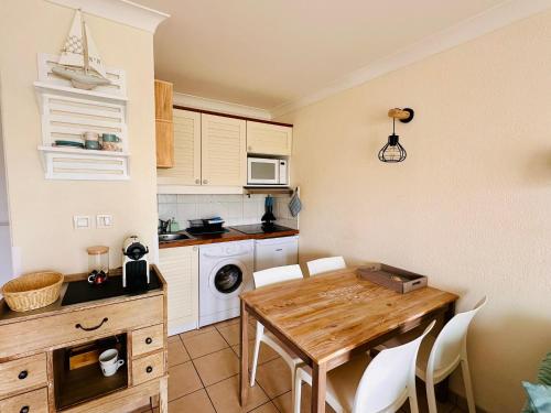 uma cozinha com uma mesa de madeira e armários brancos em Appartement rez-de-chaussée entre dunes et ocean em Lacanau-Océan