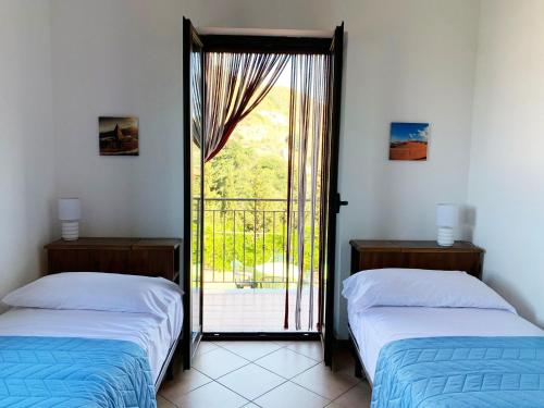 two beds in a room with a door to a balcony at Villa Maria in Castel di Tusa