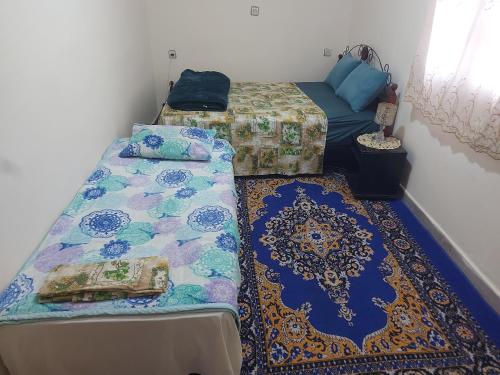a room with two beds and a couch and a rug at Chambre chez l'habitant avec famille in Agadir