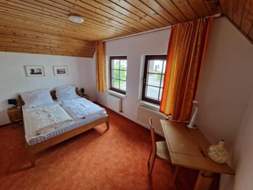 a bedroom with a bed and a desk and windows at Eifel Ferienhaus Luna in Ohlenhard